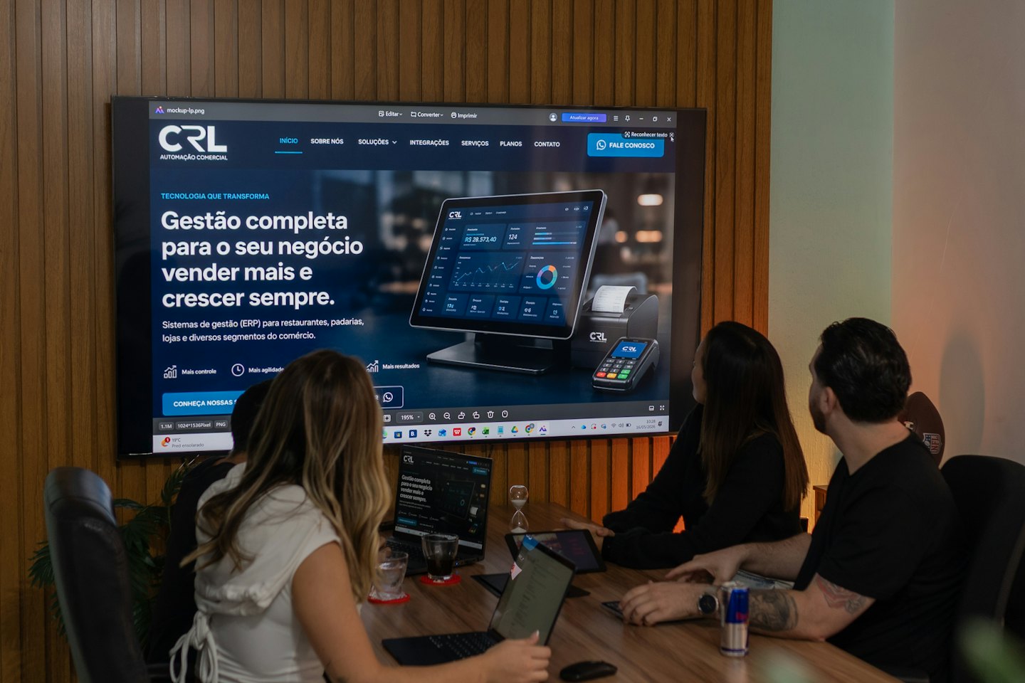 Three professionals review business management software on a conference room screen.