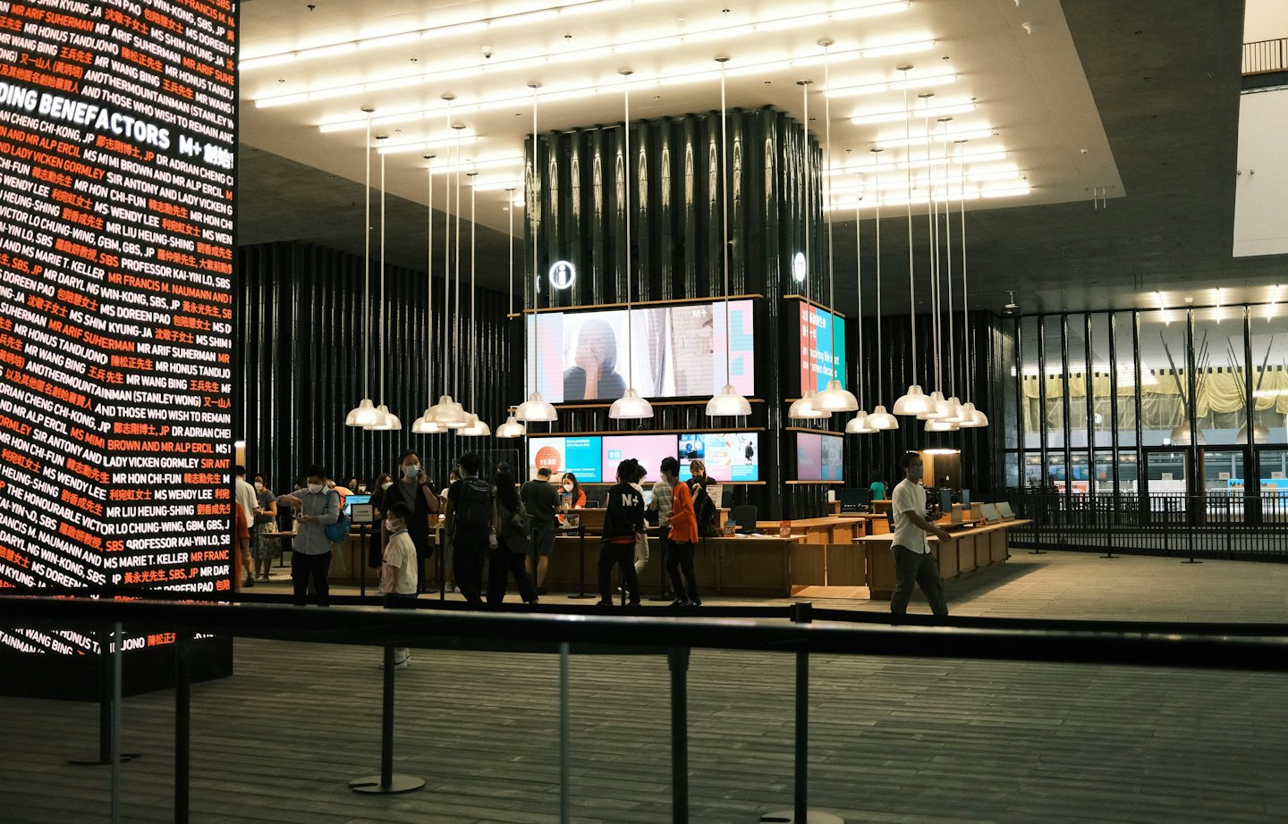 People interact at a modern reception desk with digital displays.